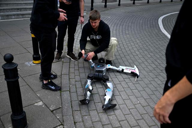 Technicians inspect a humanoid robot after it fell during a demonstration calling for the regulation of artificial intelligence development in Warsaw on September 7, 2026. Waving flags, "chanting" slogans, and marching in circles -- around thirty robots took to the streets to raise awareness for AI regulation in front of the digital affairs ministry on September 7, 2026. (Photo by Sergei GAPON / AFP)