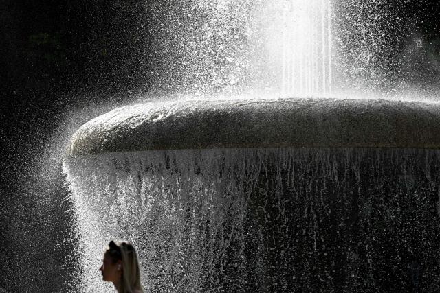 TOPSHOT - A woman walks past a water fountain in front of the Alte Oper (Old Opera) main entrance in Frankfurt am Main, western Germany, on September 7, 2026, as air temperatures reached 31 degrees Celsius. (Photo by Kirill KUDRYAVTSEV / AFP)