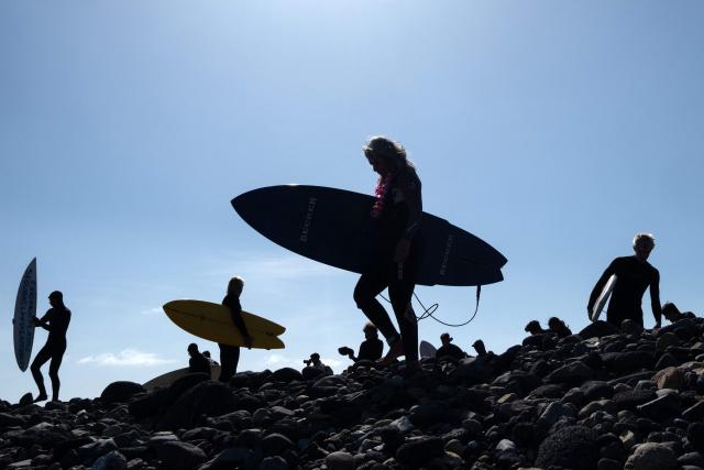 (FILES) Surfers take head to the sea to take part in a ceremony in honor of two Australians and an American surfers that went missing last week during a surfing trip at San Miguel Beach in Ensenada, Baja California State, Mexico, on May 5, 2024. On September 7, 2026, the trial of the alleged killers of two Australian surfers and one American in 2024 began at the same border resort where the crime took place. Australian brothers Jake and US Callum Robinson were murdered along with Jack Carter in April 2024 on the beaches of Ensenada, located on the Mexican Pacific coast, where the waves are strong and the area is popular with surfers who travel overland from the United States. (Photo by Guillermo Arias / AFP)