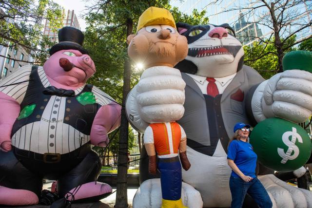 A nursing union member stands next to giant “greed” inflatables during the Boston Labor Day Parade in Boston, Massachusetts on September 7, 2026.  (Photo by JOSEPH PREZIOSO / AFP)