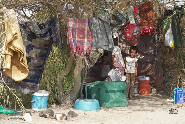 Children of internally displaced Yemeni people who fled their homes due to renewed clashes between Yemen's Saudi-backed government forces and the country's Houthi rebels, stand under a tree with their belongings after seeking shelter in Mocha, on the Red Sea coast of Yemen on September 7, 2026. (Photo by AFP)