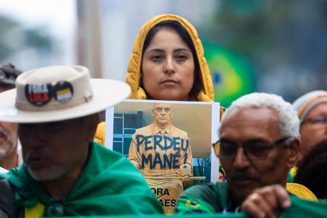 A supporter of Brazil's presidential candidate Flavio Bolsonaro holds a placard depicting Supreme Court Justice Alexandre de Moraes bearing the phrase "Perdeu, mane" ("You lost, fool") during a rally held on Independence Day in Sao Paulo, Brazil, on September 7, 2026. (Photo by Miguel SCHINCARIOL / AFP)