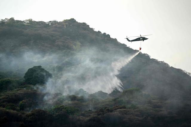 A Colombian Air Force helicopter with a bambi bucket drops water to fight a wildfire at Cerro Gordo in Yumbo, Valle del Cauca department, Colombia on September 7, 2026. (Photo by JOAQUIN SARMIENTO / AFP)