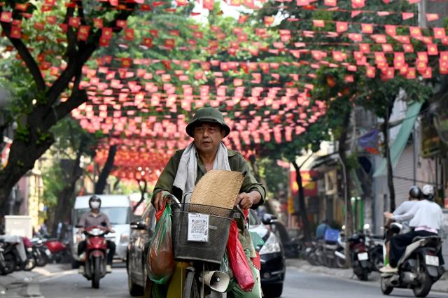 A street vendor rides a bicycle along a street in Hanoi on September 8, 2026. (Photo by Nhac NGUYEN / AFP)