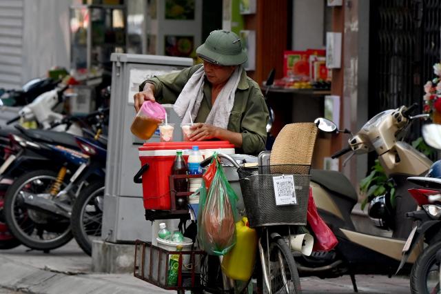 A street vendor prepares tào ph?, a soybean curd pudding, for a customer on a street in Hanoi on September 8, 2026. (Photo by Nhac NGUYEN / AFP)