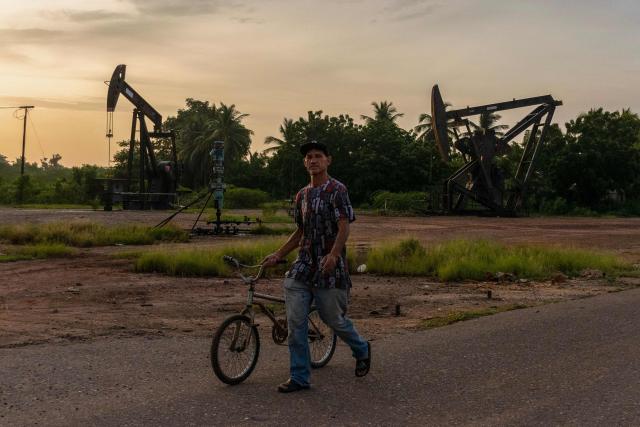 A man pushes a bicycle in front of abandoned oil wells in Maracaibo, Zulia state, Venezuela on September 7, 2026. Venezuela and US signed an agreement granting US access to more than 65 billion barrels -- almost 20 percent -- of oil in Venezuela, which holds the largest proven reserves in the world. (Photo by John Chacón / AFP)