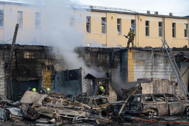 Smoke rises from a building near wrecked cars as firefighters battle a blaze following Russian missile strikes amid Russia's invasion of Ukraine, in Kyiv early on September 8, 2026. A wave of strong explosions rang out in Kyiv, AFP journalists said early on September 8, as Russia resumed strikes on the Ukrainian capital after a three-day halt. (Photo by Serhii Okunev / AFP)