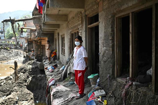 Residents look at the remains outside sludge-ridden houses in the aftermath of flash floods at Devighat in Nepal's Nuwakot district on September 8, 2026. The August 26 glacial and mountain collapse on the China-Nepal border killed at least 1,399 people, with more than 5,500 missing, including around 800 foreigners. (Photo by Pedro PARDO / AFP)