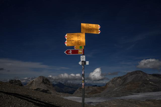 This photograph taken on September 1, 2026 shows Swiss Rando hiking trail signs near the Plaine Morte Glacier, above the resort of Crans-Montana in western Switzerland. The signs are part of Switzerland's extensive network of more than 65,000 kilometres of marked hiking trails maintained and promoted by Swiss Rando, helping visitors navigate the Alpine landscape. (Photo by Fabrice COFFRINI / AFP)