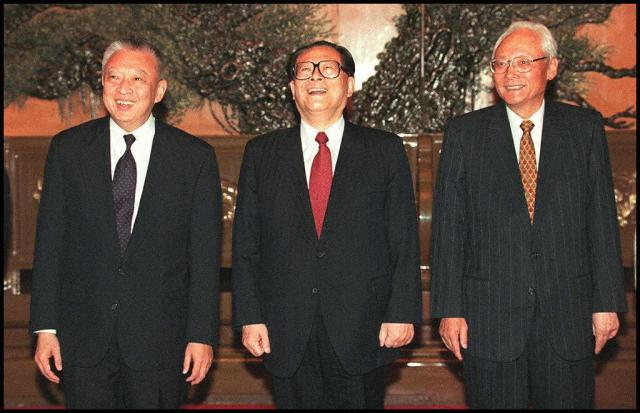 (FILES)  Hong Kong's Chief Executive-elect Tung Chee-hwa (L) laughs with Chinese President Jiang Zemin (C) and Lu Ping (R), head of the Hong Kong and Macau Affairs office before a meeting at the Great Hall of the People in Beijing on December 18, 1996. Hong Kong's first post-colonial leader Tung Chee-hwa has died aged 89, his office said early September 9, 2026.  Tung, who served as Hong Kong's chief executive from 1997 to 2005, "passed away peacefully in the presence of his beloved family members" on September 8, a statement from his office said. (Photo by Robyn BECK / AFP)