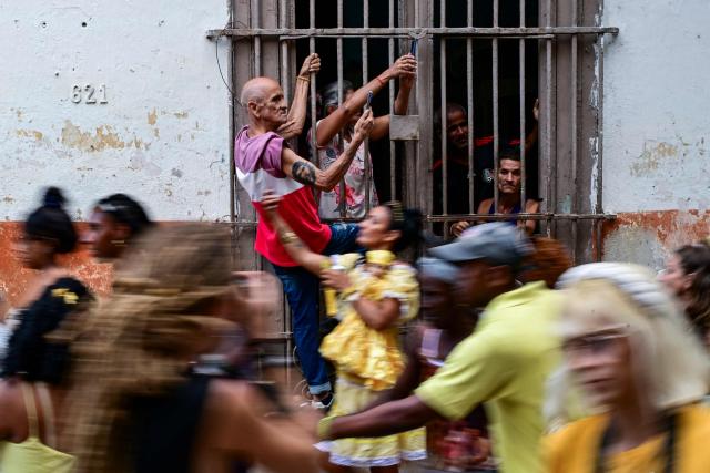 A man with a tattoo of the Argentine revolutionary leader Ernesto “Che” Guevara takes a photo with his cell phone as followers of the Virgin of Charity, Oxun in the Yoruba religion, attend a procession during the Oxun Day celebrations in Havana on September 8, 2026. (Photo by YAMIL LAGE / AFP)