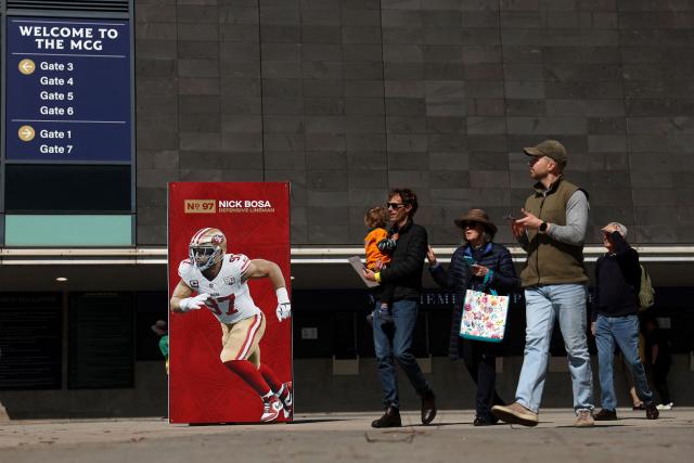 People walk past a sign at the Melbourne Cricket Ground in Melbourne on September 9, 2026. The first-ever regular-season NFL game in Australia takes place at the Melbourne Cricket Ground on September 11, 2026, featuring the San Francisco 49ers and the Los Angeles Rams. (Photo by Martin KEEP / AFP)