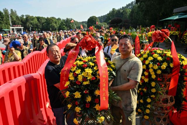 People arrive with floral arrangements to pay tribute to late Communist leader Mao Zedong at the Mao Zedong Bronze Statue Square in Shaoshan, China's central Hunan province on September 9, 2026, during the 50th anniversary of his death. (Photo by Hector RETAMAL / AFP)