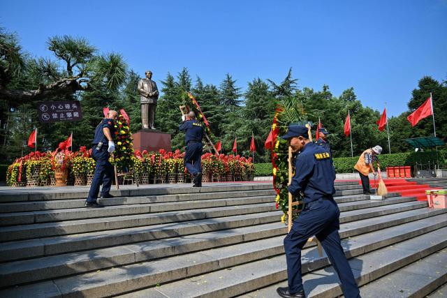 Guards receiv the floral arrangements of people to pay tribute to late Communist leader Mao Zedong at the Mao Zedong Bronze Statue Square in Shaoshan, China's central Hunan province on September 9, 2026, during the 50th anniversary of his death. (Photo by Hector RETAMAL / AFP)