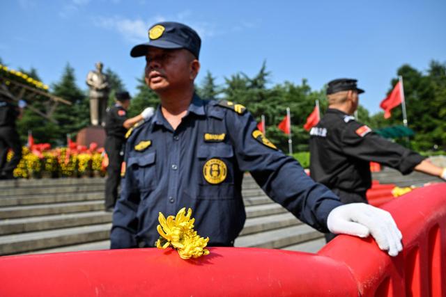 Guards wait to receive floral arrangements from people paying tribute to late Communist leader Mao Zedong at the Mao Zedong Bronze Statue Square in Shaoshan, China's central Hunan province on September 9, 2026, during the 50th anniversary of his death. (Photo by Hector RETAMAL / AFP)