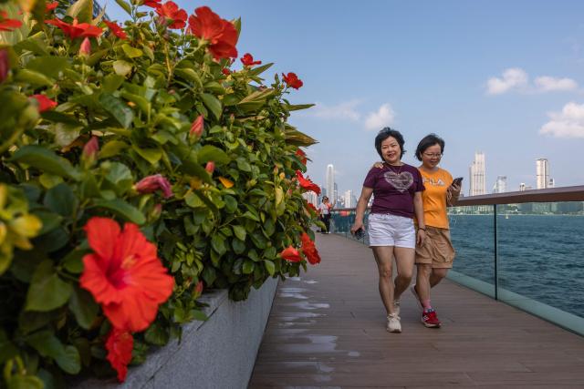 People walk along a promenade next to Victoria Harbour in Hong Kong on September 9, 2026. (Photo by Dale DE LA REY / AFP)