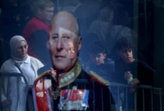 Spectators are reflected in a portrait of Norway's late King Harald V as they gather in front of the church where will be taking place the funeral service for Norway's late King Harald V at the Oslo Cathedral in Oslo, Norway, on September 9, 2026. Harald, who died on August 28, 2026 at the age of 89, will be laid to rest in the crypt of the royal mausoleum of Akershus Castle, a medieval fortress overlooking Oslo Fjord, after a service at the Oslo Cathedral. (Photo by Odd ANDERSEN / AFP)
