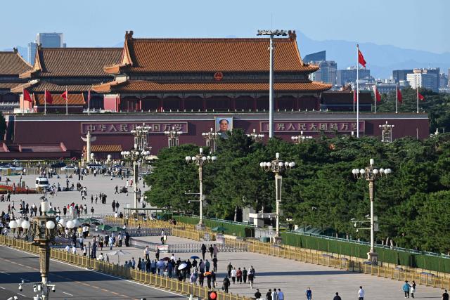 The portrait of China’s late Communist leader Mao Zedong which hangs on Tiananmen Gate (top C) is seen behind people in Tiananmen Square on the 50th anniversary of Mao’s death in Beijing on September 9, 2026. (Photo by GREG BAKER / AFP)
