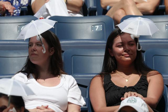 Fans protect themselves from the sun during women's singles quarter-final tennis match between China's Qinwen Zheng and Kazakhstan's Elena Rybakina on day eleven of the US Open tennis tournament at the USTA Billie Jean King National Tennis Center in New York on September 9, 2026. (Photo by TIMOTHY A. CLARY / AFP)