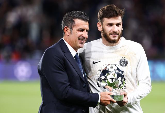 Portuguese former football player and football advisor to UEFA Luis Figo (L) gives Paris Saint-Germain's Georgian forward #07 Khvicha Kvaratskhelia (R) the UEFA Champions League Trophy for best player for the season 2025-2026 prior to the UEFA Champions League, league phase, matchday 1, football match between Paris Saint-Germain (PSG) and Slovan Bratislava at the Parc des Princes Stadium in Paris on September 9, 2026. (Photo by FRANCK FIFE / AFP)