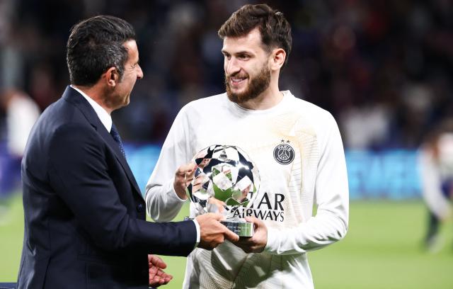 Portuguese former football player and football advisor to UEFA Luis Figo (L) gives Paris Saint-Germain's Georgian forward #07 Khvicha Kvaratskhelia (R) the UEFA Champions League Trophy for best player for the season 2025-2026 prior to the UEFA Champions League, league phase, matchday 1, football match between Paris Saint-Germain (PSG) and Slovan Bratislava at the Parc des Princes Stadium in Paris on September 9, 2026. (Photo by FRANCK FIFE / AFP)