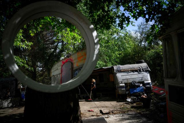 (FILES) A member of the Roma community sweeps the ground in a new settlement after being evacuated two weeks earlier from the "le moulin des marais" Roma community settlement in Nantes, western France, on August 31, 2026. Between 700 and 1,000 people, mostly Roma, live in the few "hamlets" of the Prairie de Mauves, to the east of Nantes – a haphazard collection of caravans and small houses made of mismatched planks, where pieces of wood and abandoned furniture are piled up in a jumble. Not far from the tracks of the Nantes–Angers line, the shacks in the Moulin des Marees shantytown have been partly dismantled, the site littered with pieces of wood and overturned furniture. The evictions have been criticised both by the local right wing parties, which condemns a "piecemeal" approach, and by the Nantes branch of the French left-wing party La France Insoumise, which deplores what it calls organised "wandering". (Photo by Loic VENANCE / AFP)