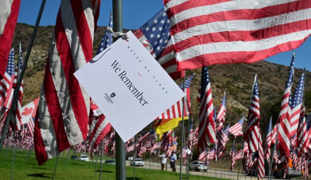 A sign reading "We Remember" is tied to a flagpole as US flags are displayed at Pepperdine University in Malibu, California, on September 9, 2026, as part of the annual Wave of Flags commemorating the September 11, 2001 attacks. (Photo by Frederic J. BROWN / AFP)