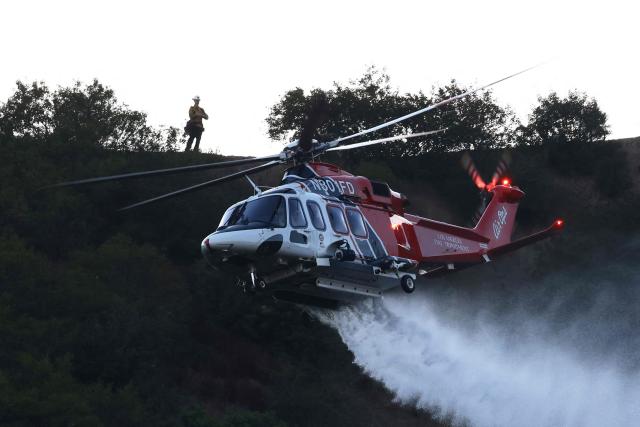 An LAFD helicopter drops water on the Getty Fire burning near the Getty Center in the Santa Monica Mountains National Recreation Area in Los Angeles on September 9, 2026. The Getty Fire broke out near the 405 Freeway in Los Angeles on September 9, 2026, burning approximately 25 acres of brush and prompting evacuation warnings for two nearby areas, although no structures were threatened. The Getty Center was closed as firefighters battled the blaze from the ground and air. (Photo by David Swanson / AFP)