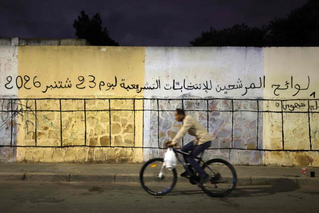 A cyclist rides past a wall being designated as space for electoral posters to be displayed of various political parties ahead of the legislative election, along a street in Sale on September 9, 2026. Campaigning for Morocco's legislative election opened on September 10, with the governing coalition led by incumbent premier Aziz Akhannouch seeking to retain power amid persistent social and economic disparities. (Photo by Abdel Majid BZIOUAT / AFP)