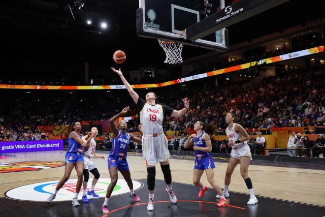 China's center #19 Zhang Ziyu (C) jumps to shoot past France's shooting guard #28 Migna Toure during the 2026 FIBA Women's Basketball World Cup quarter-final match between China and France at the Berlin Arena in Berlin on September 10, 2026. (Photo by Ronny HARTMANN / AFP)