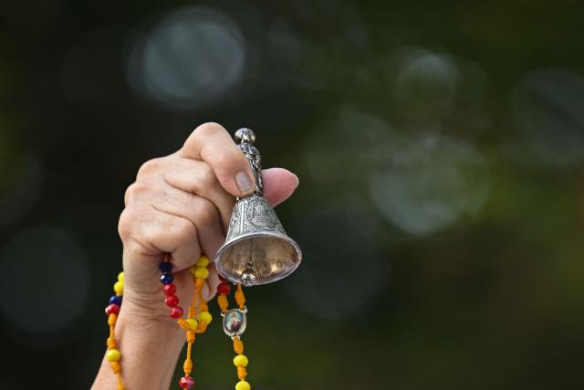 A relative of the victims of the 7.4- magnitude earthquake holds a bell and a rosary during a ceremony in honor of the victims one month after the tragedy at Maria Inmaculada Church, near Torres del Limonar, in Cali, Colombia on September 10, 2026. (Photo by JOAQUIN SARMIENTO / AFP)