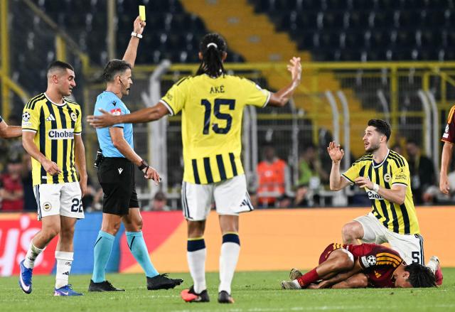 Spanish referee Jesús Gil Manzano (2L) shows a yellow card to Fenerbahçe's Turkish midfielder #05 Ismail Yuksek (R) during the UEFA Champions League first round day 1 football match between Fenerbahce SK and AS Roma at the Fenerbahce Chobani stadium in Istanbul on September 10, 2026. (Photo by Ozan KOSE / AFP)