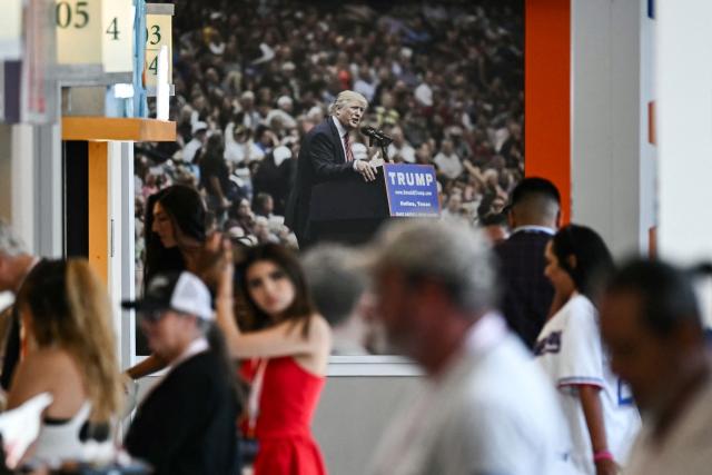 An image of US President Donald Trump is displayesd as attendees walk through the concourse at the American Airlines Center during the second day of the Republican National Committee midterm convention in Dallas, Texas on September 10, 2026. US Republicans are betting that putting President Donald Trump at the center of their campaign can rescue a party facing grim election forecasts, despite the president's negative approval ratings. A day earlier, on the first day of the midterm convention, he promised $5,000 to every American adult if Republicans retain control of Congress in November. (Photo by Kent NISHIMURA / AFP)