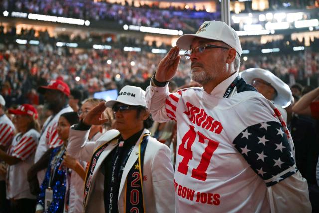 Attendees salute as a video about the 9/11 attacks is played during the second day of the Republican National Committee midterm convention at the American Airlines Center in Dallas, Texas on September 10, 2026. US Republicans are betting that putting President Donald Trump at the center of their campaign can rescue a party facing grim election forecasts, despite the president's negative approval ratings. A day earlier, on the first day of the midterm convention, he promised $5,000 to every American adult if Republicans retain control of Congress in November. (Photo by RONALDO SCHEMIDT / AFP)