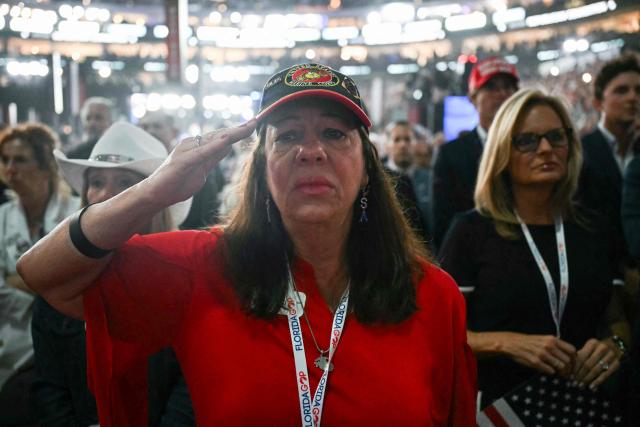 Attendees salute as a video about the 9/11 attacks is played during the second day of the Republican National Committee midterm convention at the American Airlines Center in Dallas, Texas on September 10, 2026. US Republicans are betting that putting President Donald Trump at the center of their campaign can rescue a party facing grim election forecasts, despite the president's negative approval ratings. A day earlier, on the first day of the midterm convention, he promised $5,000 to every American adult if Republicans retain control of Congress in November. (Photo by RONALDO SCHEMIDT / AFP)
