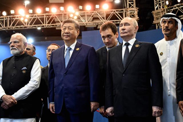In this pool photograph distributed by the Russian state agency Sputnik, India's Prime Minister Narendra Modi (L) stands alongside China's President Xi Jinping (front C) and Russia's President Vladimir Putin (front R) during the 18th BRICS Summit in New Delhi on September 12, 2026. (Photo by Kristina Solovyova / POOL / AFP)
