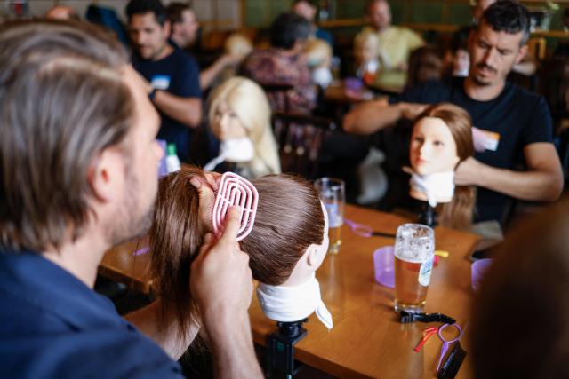 Men train to do pigtails at a doll during hair braiding course ‚dads do hair‘ in a restaurant in Munich, Bavaria, southern Germany, on September 12, 2026. (Photo by Michaela STACHE / AFP)