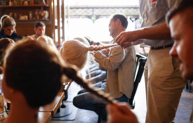 Men train to do pigtails at a doll during hair braiding course ‚dads do hair‘ in a restaurant in Munich, Bavaria, southern Germany, on September 12, 2026. (Photo by Michaela STACHE / AFP)