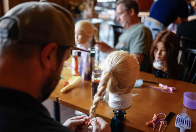 Men train to do pigtails at a doll during hair braiding course ‚dads do hair‘ in a restaurant in Munich, Bavaria, southern Germany, on September 12, 2026. (Photo by Michaela STACHE / AFP)