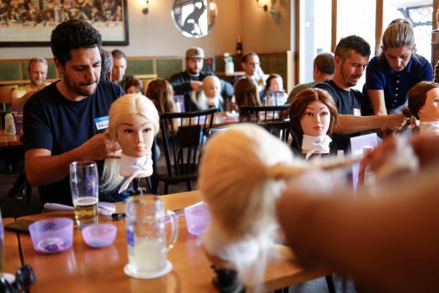Men train to do pigtails at a doll during hair braiding course ‚dads do hair‘ in a restaurant in Munich, Bavaria, southern Germany, on September 12, 2026. (Photo by Michaela STACHE / AFP)