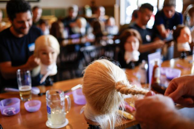 Men train to do pigtails at a doll during hair braiding course ‚dads do hair‘ in a restaurant in Munich, Bavaria, southern Germany, on September 12, 2026. (Photo by Michaela STACHE / AFP)