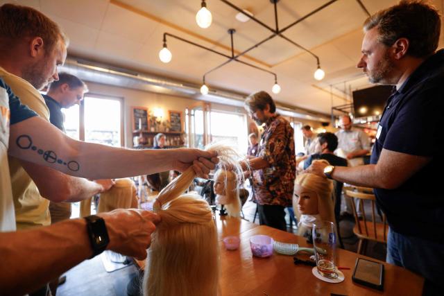 Men train to do pigtails at a doll during hair braiding course ‚dads do hair‘ in a restaurant in Munich, Bavaria, southern Germany, on September 12, 2026. (Photo by Michaela STACHE / AFP)