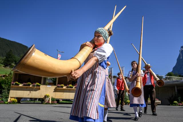 A team of alphorn players carry their instruments after performing during the first edition of the Federal Youth Yodeling Festival, in the Alpine resort of Grindelwald, Switzerland, on September 12, 2026. Grindelwald is hosting the first-ever Federal Youth Yodeling Festival, bringing together young talents aged 5 to 25 from across Switzerland to celebrate yodeling, alphorn and Buchel playing, as well as flag throwing. (Photo by Fabrice COFFRINI / AFP)