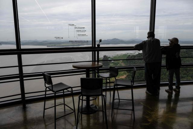 Visitors look across the confluence of the Han River and Imjin River towards North Korea from South Korea's Odusan Unification Observatory near the Demilitarized Zone (DMZ) dividing the two Koreas, in Paju on September 12, 2026. (Photo by Lillian SUWANRUMPHA / AFP)