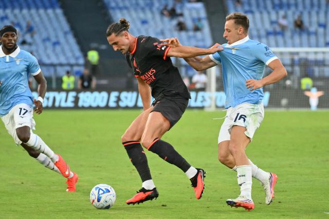 AC Milan's French midfielder #12 Adrien Rabiot (C) and Lazio's Italian midfielder #16 Davide Frattesi (R) fight for the ball during the Italian Serie A football match between Lazio and AC Milan at the Olympic Stadium in Rome on September 12, 2026. (Photo by Alberto PIZZOLI / AFP)