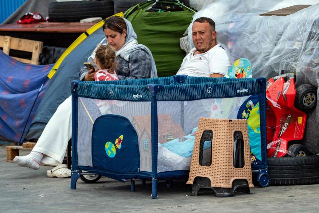 Migrants rest near the Tarajal warehouses, used by authorities as a temporary migrant reception facility (CATE), in Ceuta on September 12, 2026. More than 70,000 migrants streamed into Ceuta from neighbouring Morocco on July 30 and 31, in an unprecedented rush that left scores dead. Thousands remain in the small city, increasing tensions with increasingly frustrated locals who demand their expulsion and a return to normality. The crisis has generated a constant churn of negative headlines and dominated the political debate for six weeks. (Photo by Antonio Sempere / AFP)