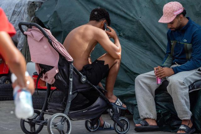 Migrants rest near the Tarajal warehouses, used by authorities as a temporary migrant reception facility (CATE), in Ceuta on September 12, 2026. More than 70,000 migrants streamed into Ceuta from neighbouring Morocco on July 30 and 31, in an unprecedented rush that left scores dead. Thousands remain in the small city, increasing tensions with increasingly frustrated locals who demand their expulsion and a return to normality. The crisis has generated a constant churn of negative headlines and dominated the political debate for six weeks. (Photo by Antonio Sempere / AFP)