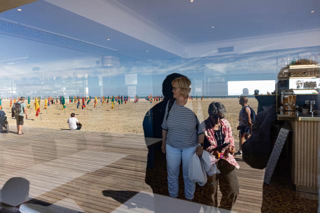 This photograph shows people walking along the beach reflected in a bar window during the 52nd edition of the Deauville american film festival in Deauville on September 12, 2026. (Photo by Alain JOCARD / AFP)