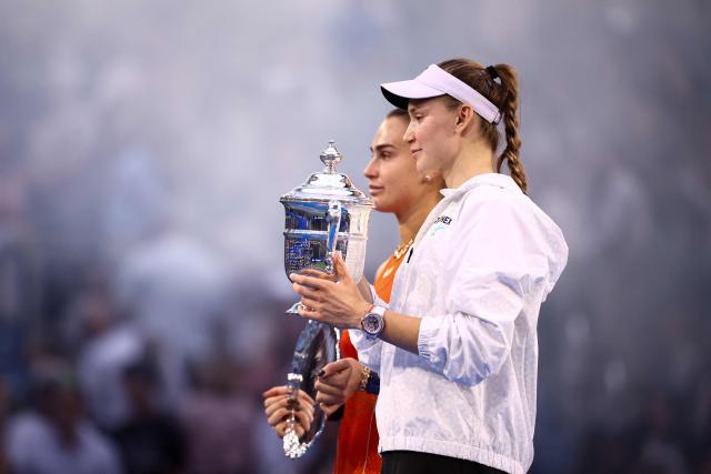 Kazakhstan's Elena Rybakina holds up the winner's trophy next to Belarus's Aryna Sabalenka after winning the women's singles final tennis match on day fourteen of the US Open tennis tournament at the USTA Billie Jean King National Tennis Center in New York City on September 12, 2026. (Photo by CHARLY TRIBALLEAU / AFP)