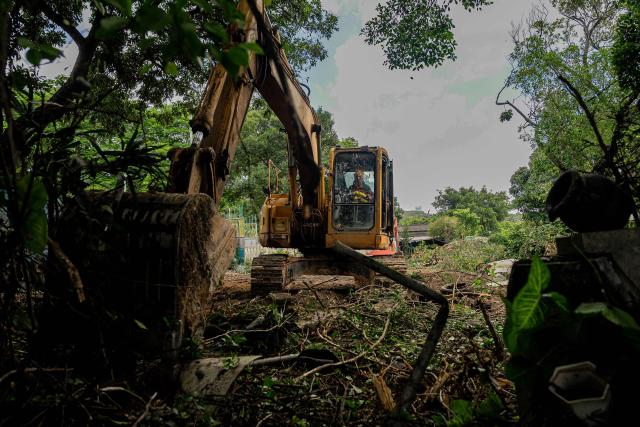 An excavator operates on resumed land during clearance work in the Kwu Tung area of Hong Kong’s northern New Territories, on June 23, 2026. An area roughly a third of Hong Kong including villages, natural wetlands and farmland are being converted into the "Northern Metropolis", an ambitious project aimed at deepening integration with the mainland, diversifying the economy and providing new homes. (Photo by Leung Man Hei / AFP) / TO GO WITH AFP STORY: Hong Kong-economy-technology-development, FOCUS by Catherine LAI